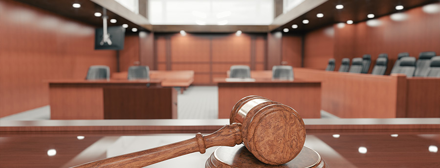 Picture of an empty court room. The focus of the picture is centered on a gavel. 