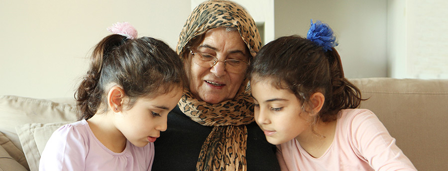 A picture of an older woman reading to two children.